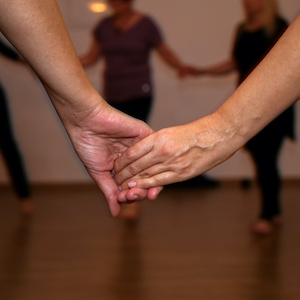 Two women holding hands during a women's dance circle